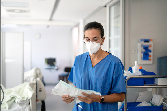 ICU doctor in mask preparing supplies in hospital ward