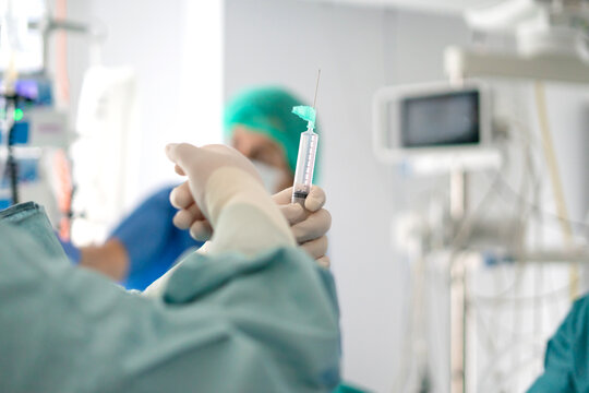 Doctor holding syringe in ICU during emergency care