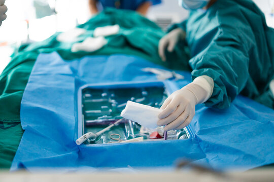Hand of doctor preparing sterile kit for tracheotomy procedure in ICU