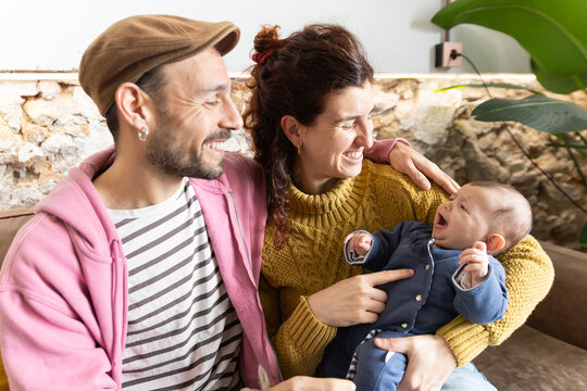 Happy new mom and dad cuddling newborn at home