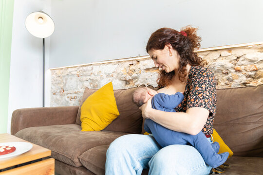New mother breastfeeding newborn in cozy home moment