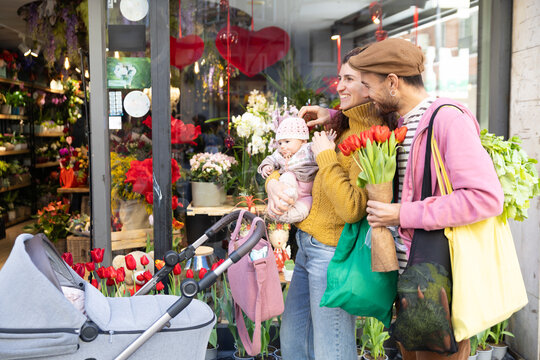 Happy new family with newborn at flower shop in city