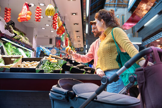Happy new parents shopping at market with newborn stroller