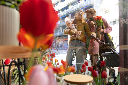 Happy parents with newborn by flower shop window stroll