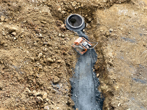 Construction site with compactor and concrete pipe