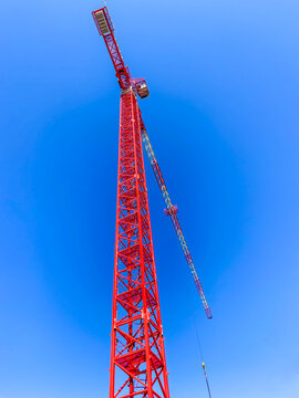 Red crane on construction site against a clear blue sky