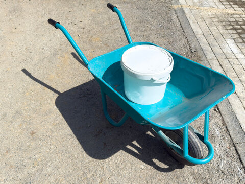 Wheelbarrow and bucket on construction site pavement