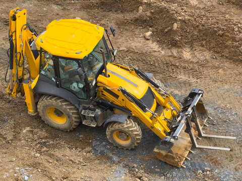 Yellow excavator operating on construction site terrain