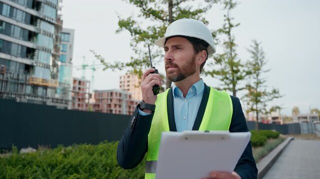 Caucasian contractor foreman talking walkie talkie check blueprint building plan professional worker adult builder male in hardhat talk remote radio man architect engineer repairman work construction