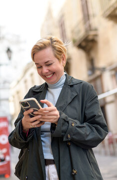 Smiling woman using smartphone while sightseeing in Lecce