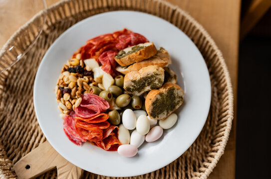 Tabla gourmet de aperitivos con embutidos, aceitunas y pan artesanal sobre plato blanco