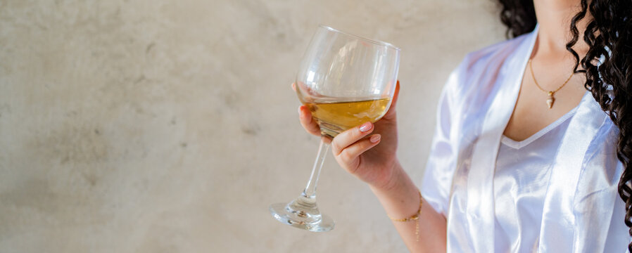 Mujer elegante sosteniendo copa de vino blanco en ambiente minimalista y sofisticado
