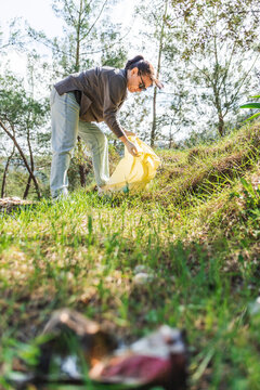 Volunteer picking up litter in forest for community cleanup