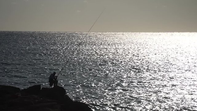 View of man fishing with glittering blue sea near Paphos, Yeroskipou, Paphos, Cyprus, Mediterranean Sea