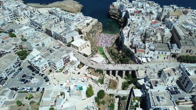 Drone aerial footage of Polignano a Mare historic coastline and Lama Monachile beach with turquoise Adriatic Sea in Puglia, southern Italy.