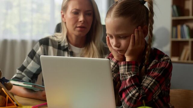 Stressed Caucasian child little girl mom studying problem laptop difficult task sad family kid schoolgirl daughter pupil learner upset remote learning failure at home parent woman female mother help