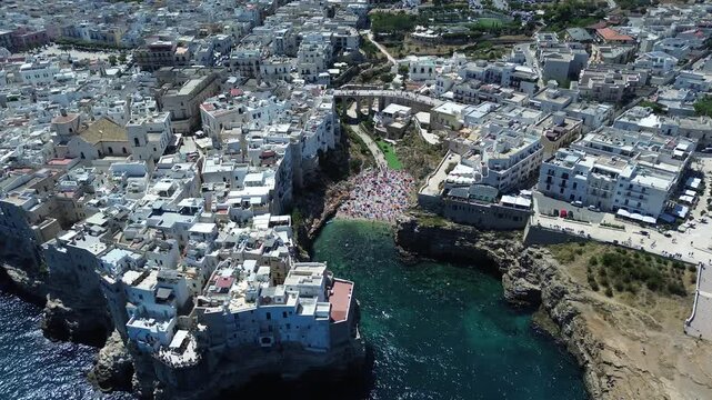 Drone aerial footage of Polignano a Mare historic coastline and Lama Monachile beach with turquoise Adriatic Sea in Puglia, southern Italy.