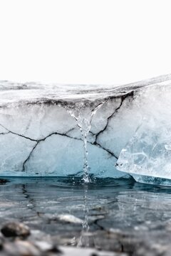 Melting glacier ice with water trickling through cracks into cold reflective pool