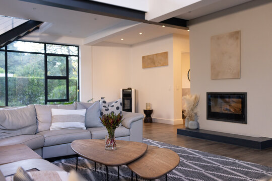 Light gray L-shaped sectional sofa is anchoring modern living room with nested wooden coffee tables