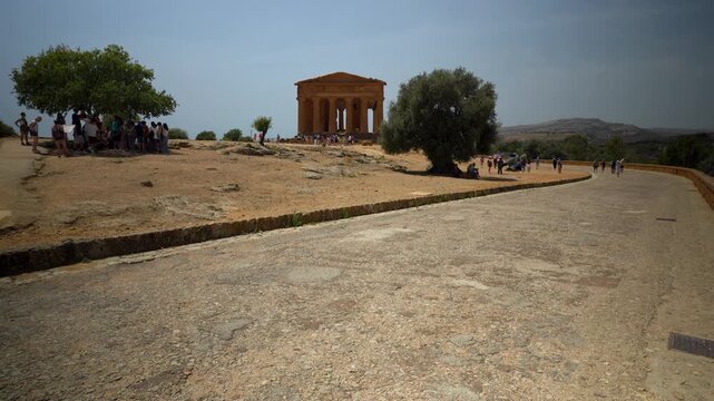 4K video of the Temple of Concordia in Agrigento, Sicily, Italy. Ancient Greek ruins with Doric columns surrounded by olive trees and tourists exploring the archaeological site.