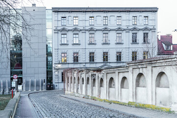 Gmach Miejskiej Biblioteki Publicznej w Opolu. Zabytkowa kamienica połączona z nowoczesną szklaną architekturą, ulica z kostki brukowej i zabytkowy mur w tle. © Henryk Niestrój