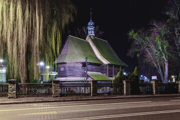 Zabytkowy drewniany kościół św. Barbary w Strzelcach Opolskich nocą. Iluminowana tradycyjna architektura sakralna z drewna, nocny pejzaż miejski, śląskie zabytki. © Henryk Niestrój