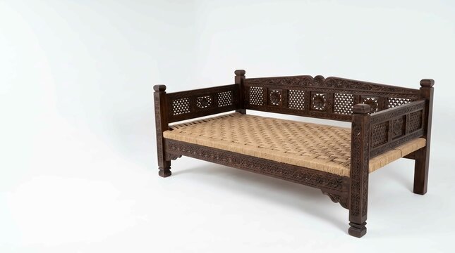 An ornate dark wooden daybed featuring intricate hand carved details and a woven fiber seat surface