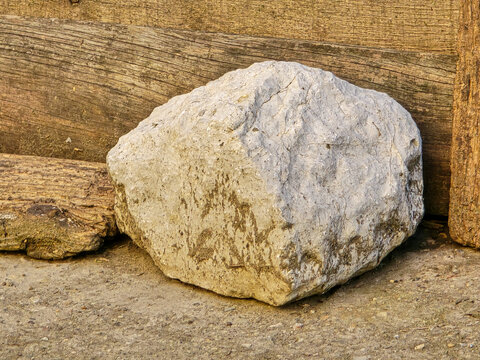 Large white limestone rock in front of old weathered wooden logs