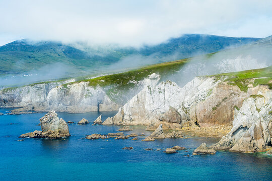 Misty White Cliffs of Ashleam on Achill Island, County Mayo, Ireland. Dramatic Atlantic sea cliffs and turquoise water on the Wild Atlantic Way.