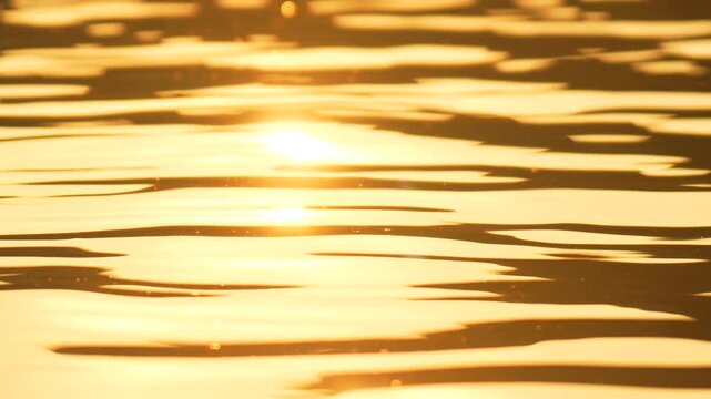 Abstract sea summer ocean sunset nature background. Small waves on golden water surface in motion blur with golden bokeh lights from sun. Holiday, vacation and recreation. Weather and climate change
