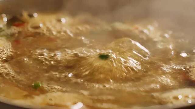 Closeup of bubbling broth in a pot steam rising culinary preparation.
