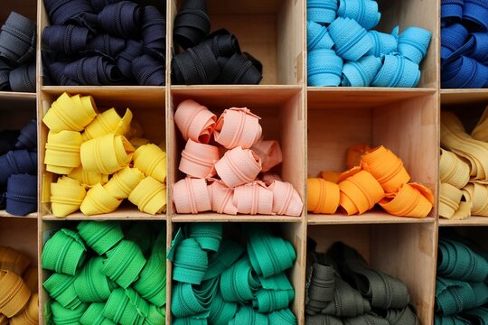 Colorful zippers organized by shade filling wooden compartments