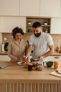 Couple making toast together in a modern kitchen