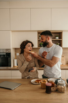 Happy couple feeding each other toast during morning breakfast