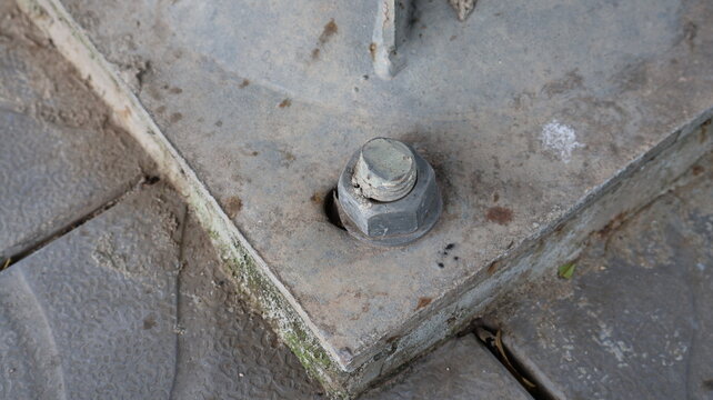 Close up of a large metal bolt and nut on concrete