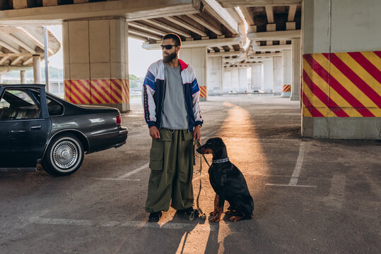 Young bearded guy walks pet in urban environment. Hip hop culture