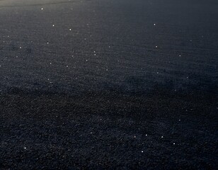 Fototapeta premium Minimalist black volcanic sand texture close up featuring tiny sparkling quartz crystals capturing natural dark volcanic beach soil background design