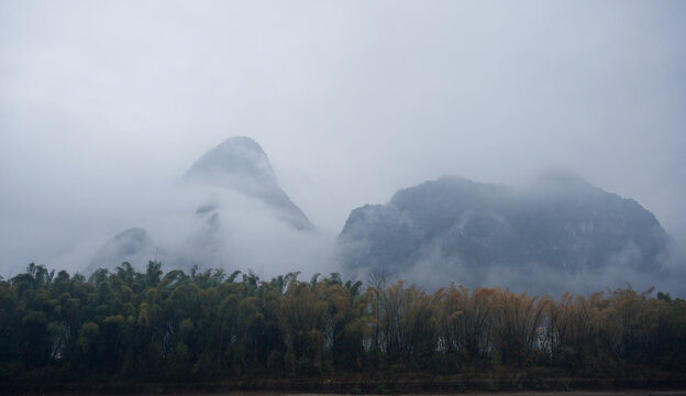 Mist drifts across the karst peaks of the Li River, veiling bamboo groves and mountains in a Guangxi landscape