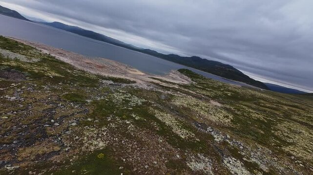 Aerial flight over Norwegian mountain plateau with lake and remote road