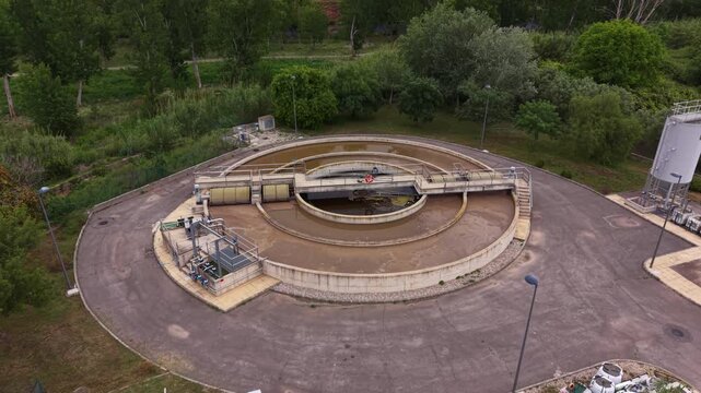 Overhead view of a circular secondary clarifier at a municipal sewage treatment facility, featuring a central sedimentation tank enclosed by an outer aeration basin, with access walkways
