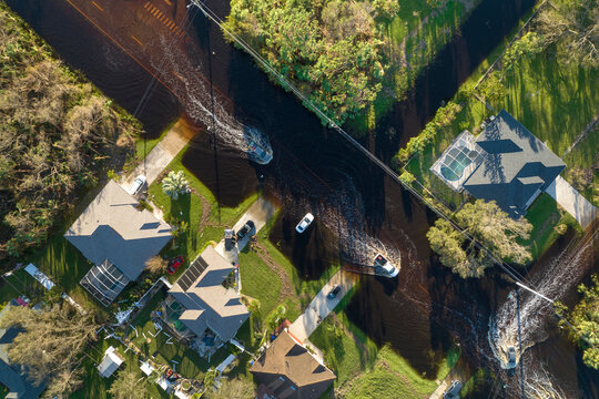 Flooded american street with moving vehicles and surrounded with water houses in Florida residential area. Consequences of hurricane natural disaster