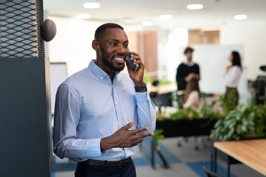 Smiling black businessman talking on smartphone in office
