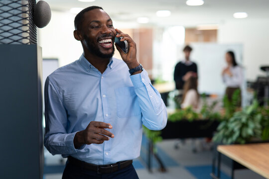 Black businessman discussing on phone feeling happy in office