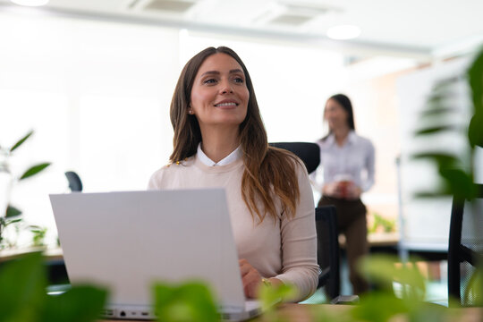 Professional woman smiling looking away with laptop in office