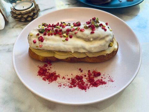 Close up of gluten free, lactose free pastry with creamy filling, white coating and pistachio topping. Gourmet healthy dessert with stylish presentation.