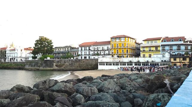  Historic colonial buildings in Casco Antiguo overlook a small beach where people gather near the waterfront, surrounded by vibrant architecture and tropical light.