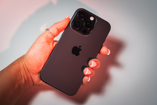 TALLINN, ESTONIA - MAY 18, 2026: A close-up of a woman's hand holding a dark gray iPhone 16 Pro smartphone, demonstrating the back panel and camera system