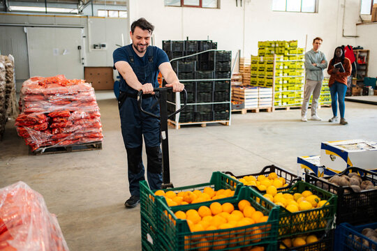 Male worker moving fresh fruit crates in warehouse