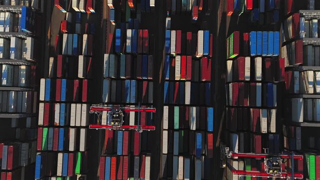 Automated crane moving above container stacks in aerial top down view