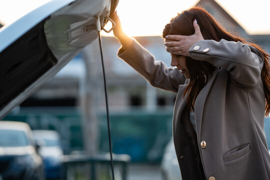 Frustrated woman experiencing car breakdown with open hood